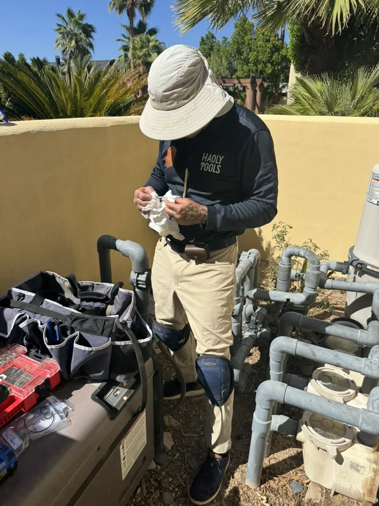 Haolys technician working on a component beside pool equipment