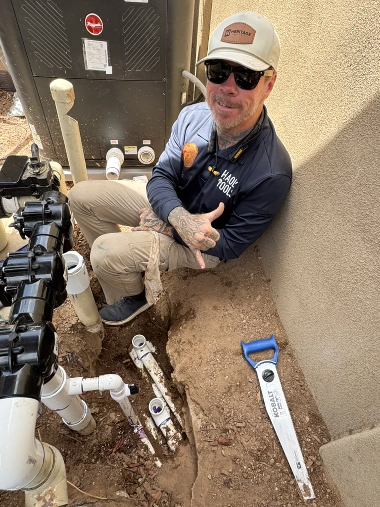 Technician seated in an excavated pool-plumbing trench