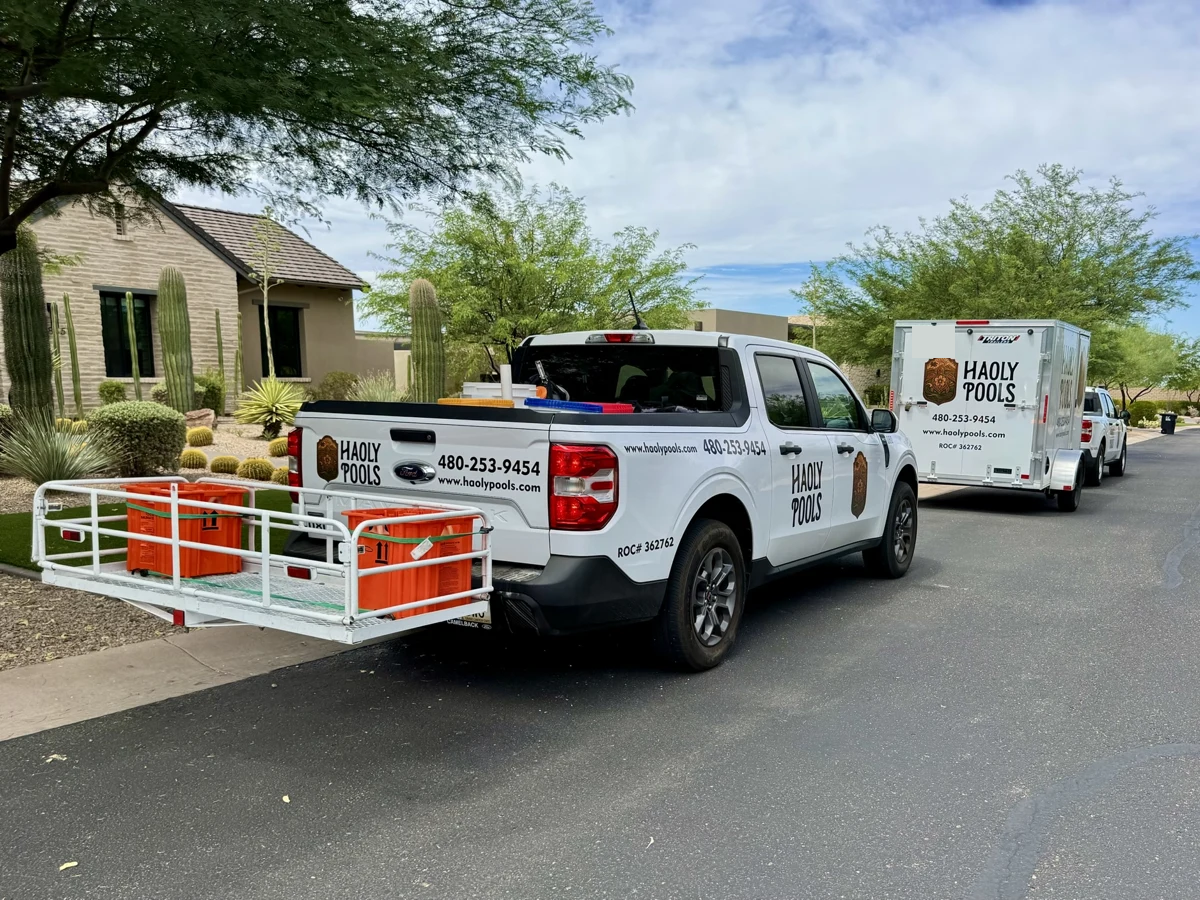 Haoly Pools service trucks and trailer along a neighborhood street