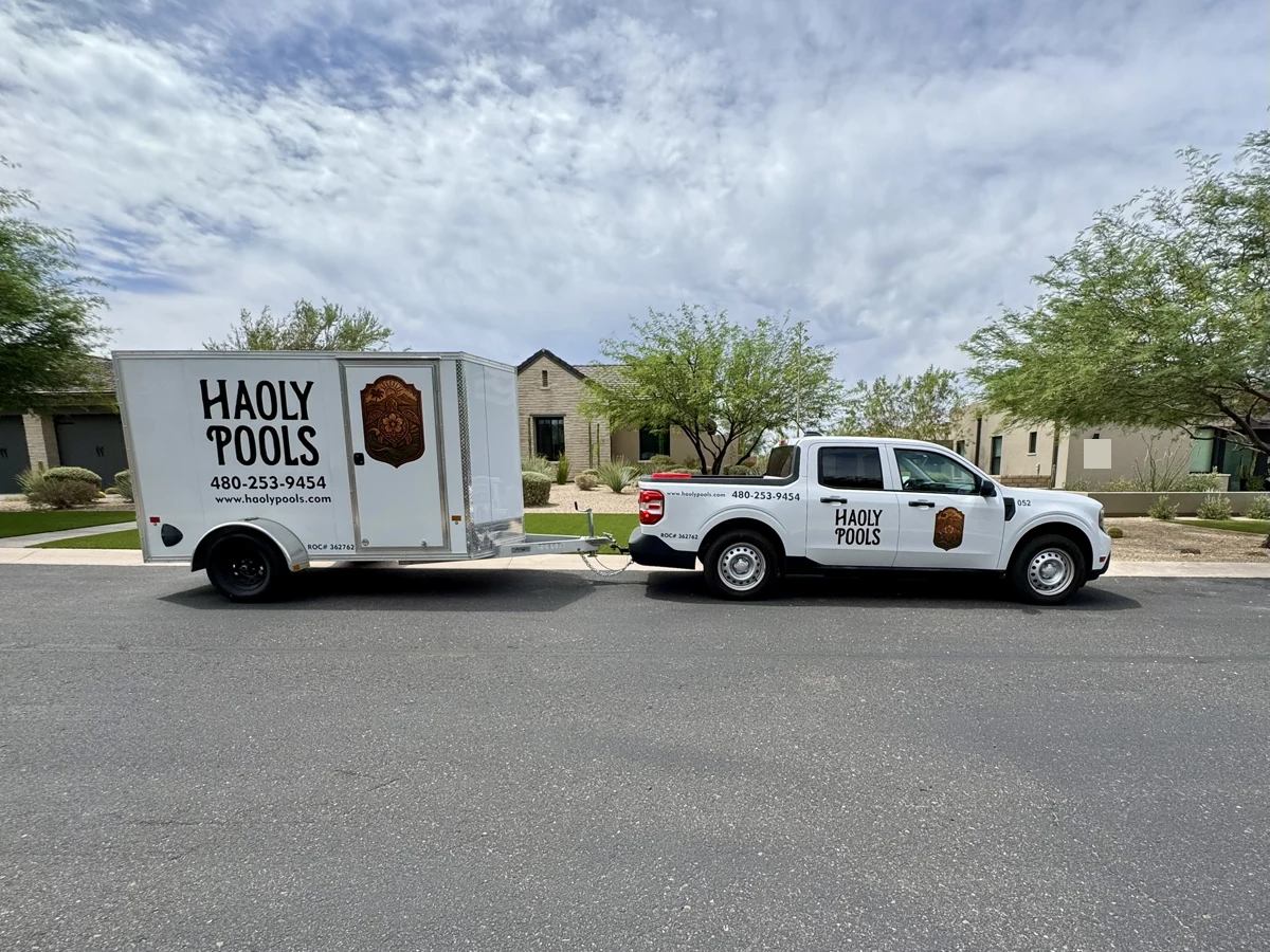 Haoly Pools truck and enclosed trailer parked on a residential street