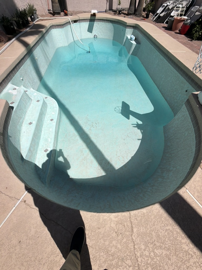 The drained pool with its worn pale-aqua interior.